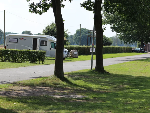 Reisemobilstellplatz in Rodewald mit gepflastertem Weg, Wohnmobil und gepflegten Grünanlagen.