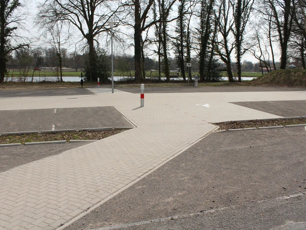 Paving stones form parking spaces suitable for vehicles between bare deciduous trees at the RV park.