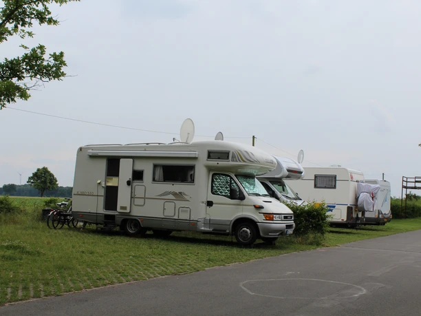 Wohnmobilstellplatz mit grüner Umgebung, gepflasterten Stellflächen und freiem Blick auf weites Land.