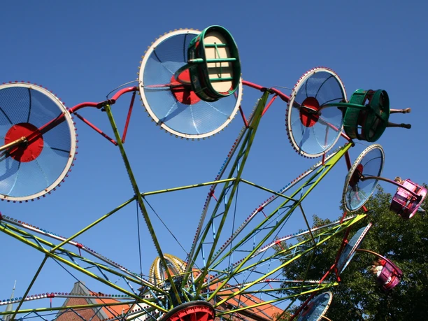 Altstadtfest Nienburg A colorful Ferris wheel with rotating gondolas in front of a bright blue sky during the Old Town Festival.