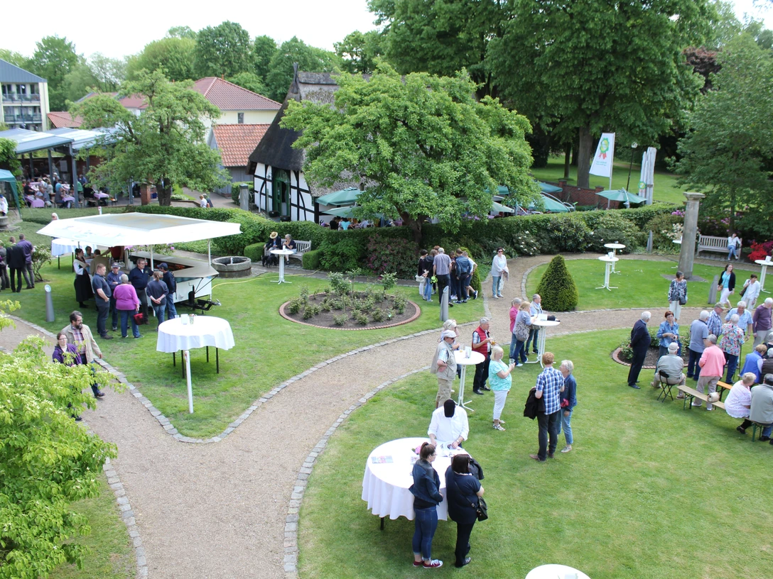 Nienburger Spargelfest Menschen genießen ein Spargelfest im Freien mit Ständen und Tischen, umgeben von grüner Natur.People enjoy an outdoor asparagus festival with stalls and tables, surrounded by green nature.Folk nyder en udendørs aspargesfestival med boder og borde, omgivet af grøn natur.Mensen genieten van een openlucht aspergefestival met kraampjes en tafels, omgeven door groene natuur.