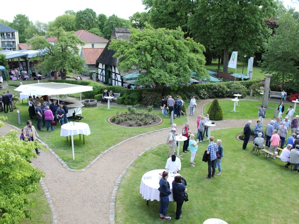 Nienburger Spargelfest People enjoy an outdoor asparagus festival with stalls and tables, surrounded by green nature.