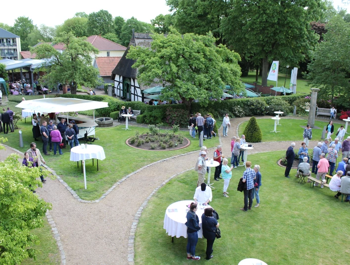 Nienburger Spargelfest Menschen genießen ein Spargelfest im Freien mit Ständen und Tischen, umgeben von grüner Natur.People enjoy an outdoor asparagus festival with stalls and tables, surrounded by green nature.Folk nyder en udendørs aspargesfestival med boder og borde, omgivet af grøn natur.Mensen genieten van een openlucht aspergefestival met kraampjes en tafels, omgeven door groene natuur.
