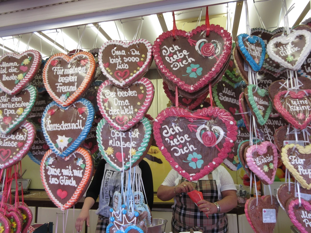 Bunte Lebkuchenherzen mit Schriftzügen hängen nebeneinander an einem Verkaufsstand.Colorful gingerbread hearts with lettering hang side by side on a stall.Farverige honningkagehjerter med bogstaver hænger side om side på en bod.Kleurrijke harten van peperkoek met letters hangen naast elkaar aan een kraam.