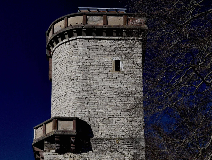 Kaiser-Friedrich-Turm (Altendorfer Berg)_Außenansicht Runder Aussichtsturm aus hellem Stein mit Zinnenkranz im Einbecker Stadtwald vor tiefblauem Himmel