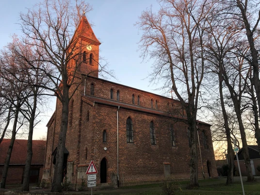 Kirche Friedewalde Backsteinkirche aus dem 19. Jahrhundert mit hohem Turm, umgeben von kahlen Winterbäumen.
