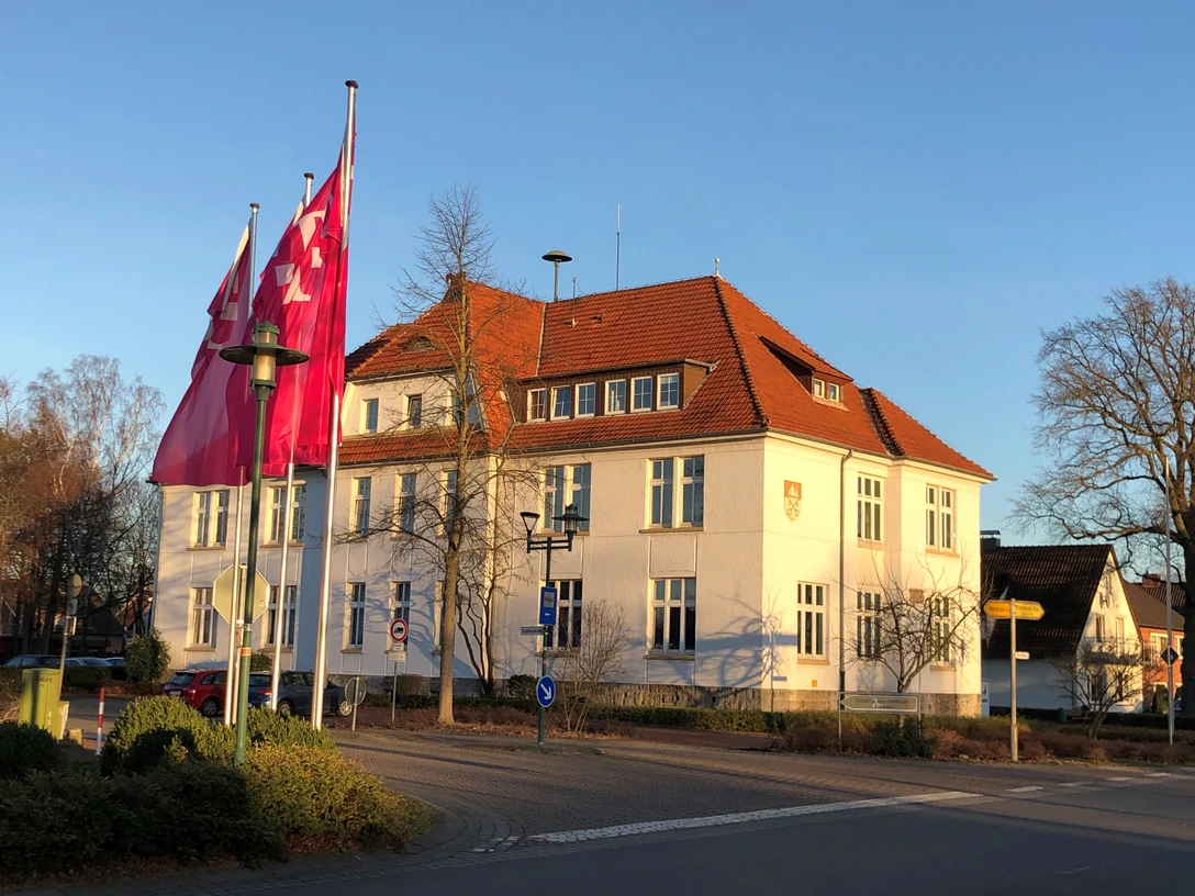 Rathaus Lahde Ein historisches Gebäude im späten Nachmittagslicht, mit rosa Fahnen rechts davor.