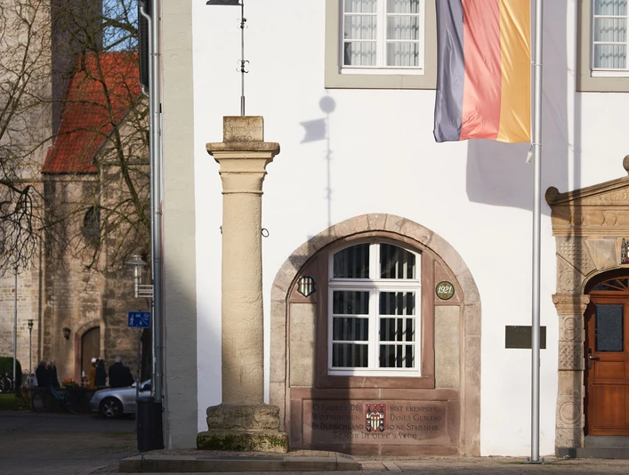 Rolandsäule auf dem Marktplatz Die Rolandsäule steht auf einem Marktplatz vor einem historischen Gebäude mit deutscher Flagge.