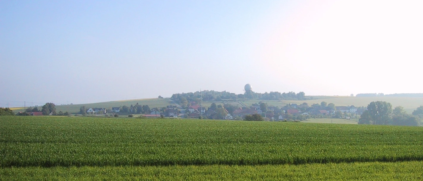 Ausblick vom Kaiserstein Blick über weitläufige, grüne Felder auf eine ferne Ortschaft am Horizont unter klarem Himmel.