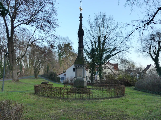 Mühlenwall_Denkmal an Krieg 1870/71 Steinernes Kriegsdenkmal mit Spitze im Park, umgeben von Hecken und Bäumen am Mühlenwall Einbeck.
