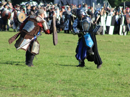 Conquest of Mythodea Zwei mittelalterlich gekleidete Teilnehmer kämpfen bei einem Live-Rollenspiel-Event auf einer Wiese.Two participants dressed in medieval costumes fight in a meadow during a live role-playing event.To deltagere klædt i middelalderkostumer kæmper på en eng under et live-rollespil.Twee deelnemers gekleed in middeleeuwse kostuums vechten in een weiland tijdens een live rollenspel.
