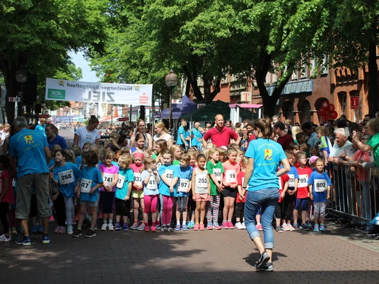 Nienburger Spargellauf Eine Gruppe von Kindern steht erwartungsvoll am Start des Nienburger Spargellaufs, umgeben von Zuschauern.