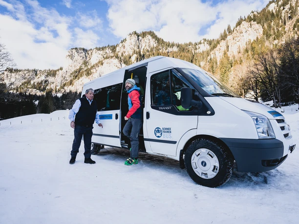 Arrivée du bus des randonnées en neige à Meniggrund Un client descend du bus de la tournée des neiges. Le chauffeur l'aide à le faire.