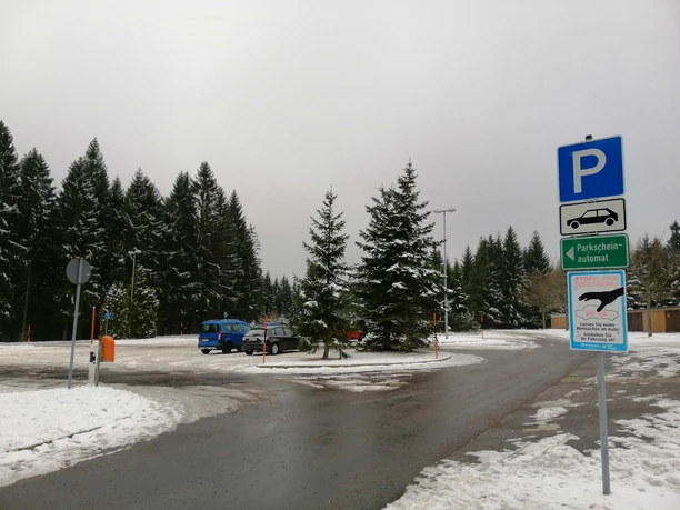 Parkplatz Oberbärenburg Verschneiter Parkplatz mit Pkw, Wegweiser und umgeben von Tannen, Winterlandschaft.