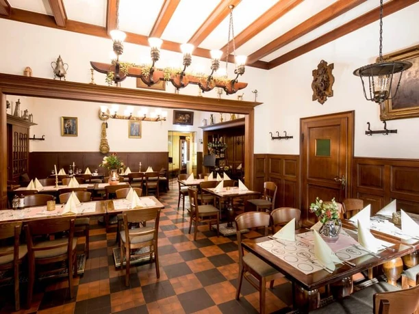 Restaurant Haus Scholzen Rustikal eingerichtetes Restaurant mit Holzbalken an der Decke und Bilder in goldenen Rahmen an den Wänden