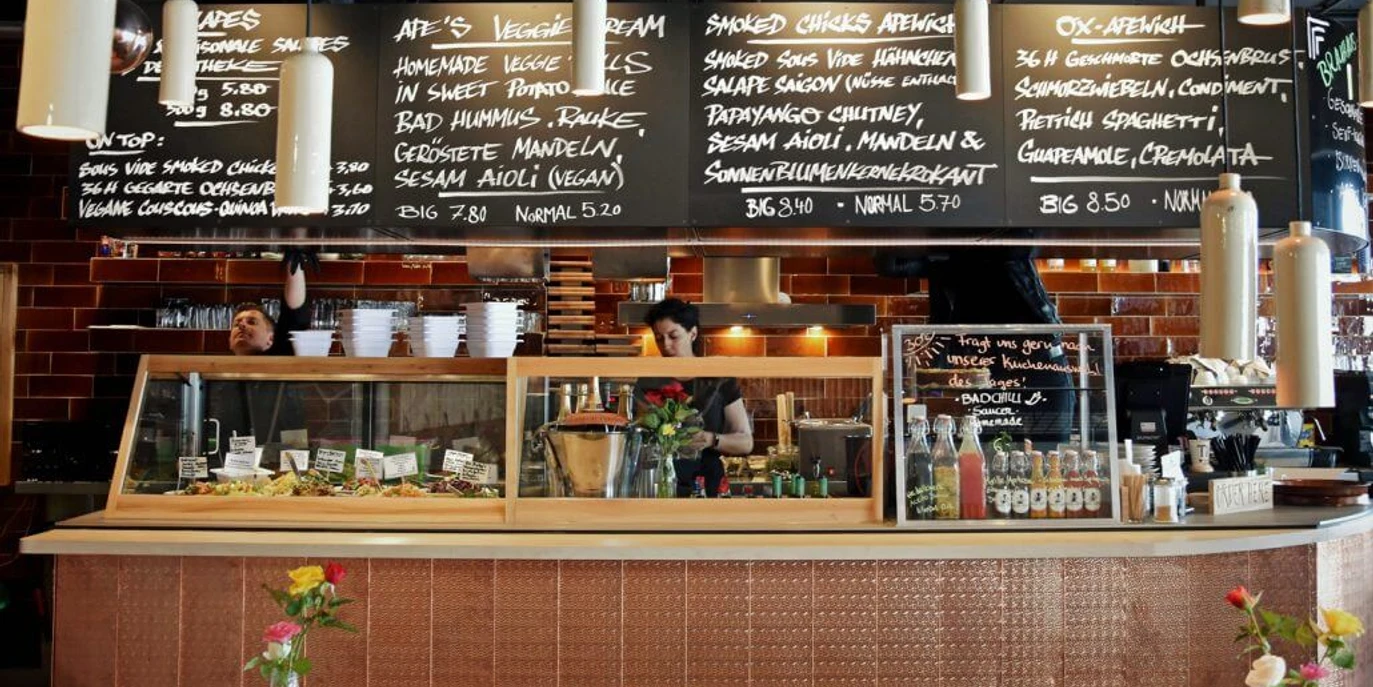 Bad Ape Theke Gekachelte Theke im Bistro. Von der Decke hängen Kreidetafeln mit dem aktuellem Menü.Tiled bar in the bistro. Chalkboards hanging from the ceiling with the current menu.