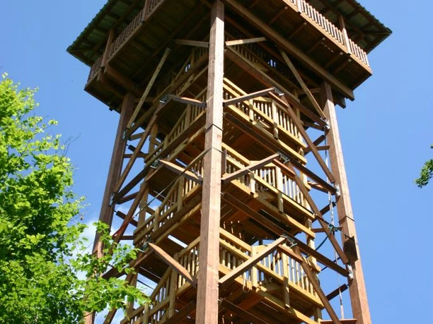 Vörden, Aussichtsturm Hungerberg Holzaussichtsturm auf dem Hungerberg, umgeben von grünen Bäumen, ragt vor blauem Himmel empor.