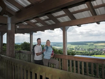 Auf dem Hungerbergturm Ein Paar genießt die weite Aussicht vom überdachten Holz-Aussichtsturm auf weite, grüne Landschaften.