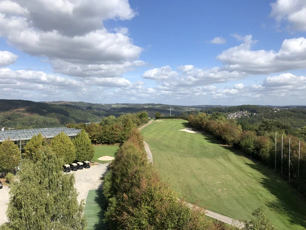 Förderturm Lüderich Weitläufige Golfanlage in grüner Hügellandschaft unter blauem Himmel mit weißen Wolken.