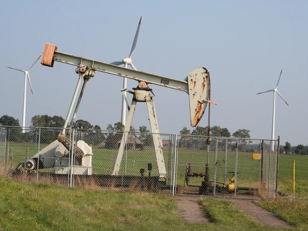 Oil pump in Steyerberg in front of wind turbines in a green field landscape shows energy generation in harmony.