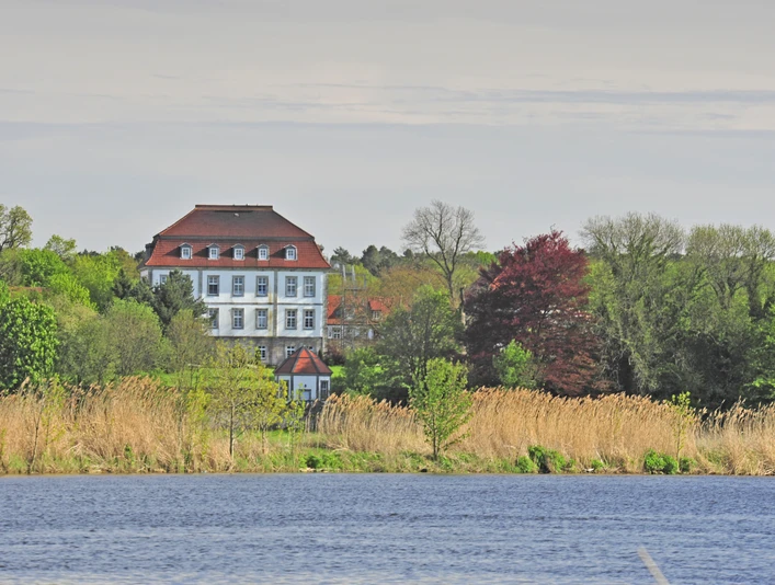 Gut Neuhof an der Weser Herrenhaus von Bäumen umgeben, mit Ziegelsteindach und Seeblick, lädt zum Entdecken ein.
