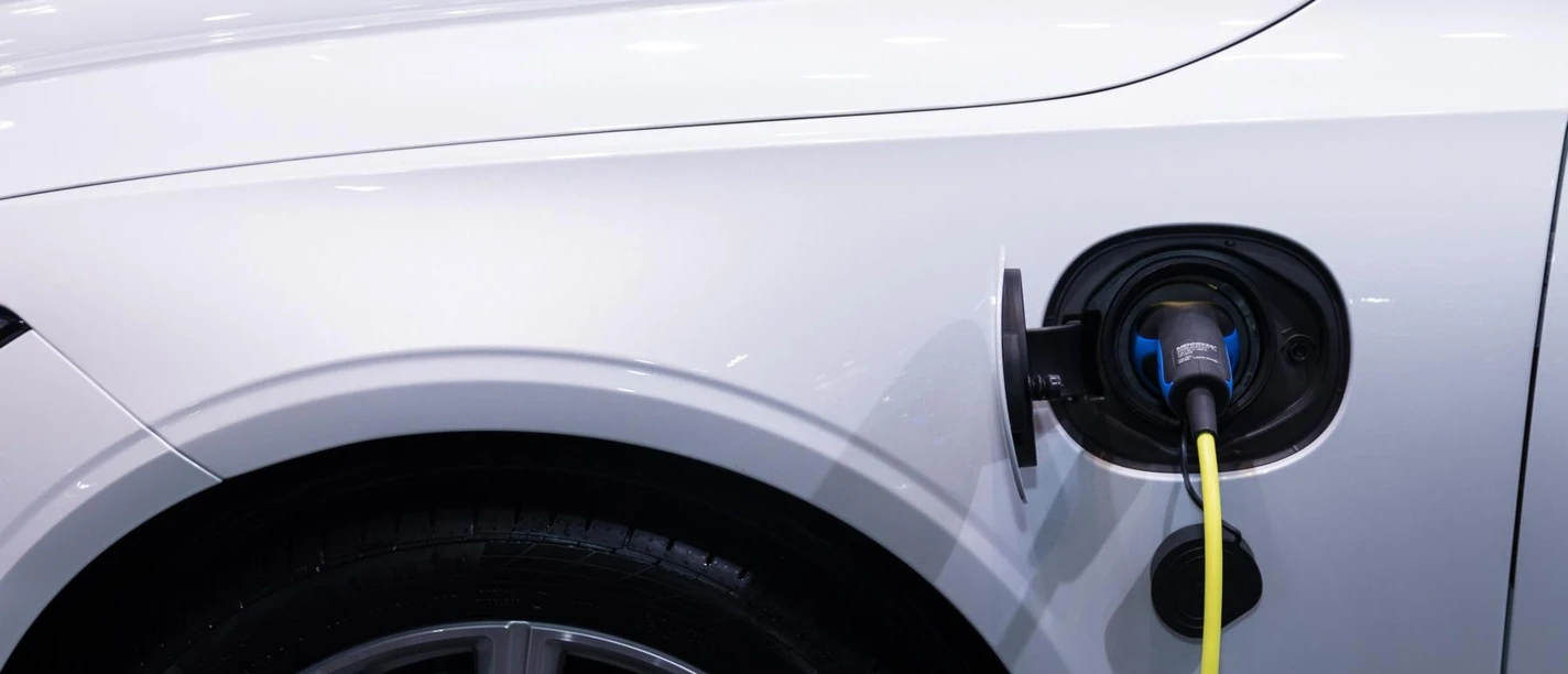 beispiel-e-mobilitaet_pexels-rathaphon-nanthapreecha.JPG Nahaufnahme eines weißen Elektroautos mit angeschlossenem Ladekabel an der Ladebuchse.