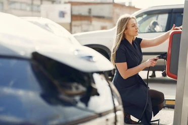 beispiel-e-mobilitaet_pexels-gustavo-fring-.JPG Eine Frau in schickem Kleid nutzt eine Ladesäule für Elektrofahrzeuge auf einem Parkplatz.