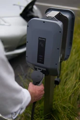 beispiel-e-mobilitaet_pexels-ed-harvey.JPG Ein Mann behandelt das Kabel einer Ladestation für Elektrofahrzeuge im Grünen.
