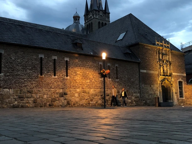 Domschatzkammer Außenansicht Dämmerung Außenansicht der Domschatzkammer im Dämmerlicht mit historischem Mauerwerk, beleuchtet von einem Straßenlaternenlicht, im Hintergrund erhebt sich ein Kirchturm
