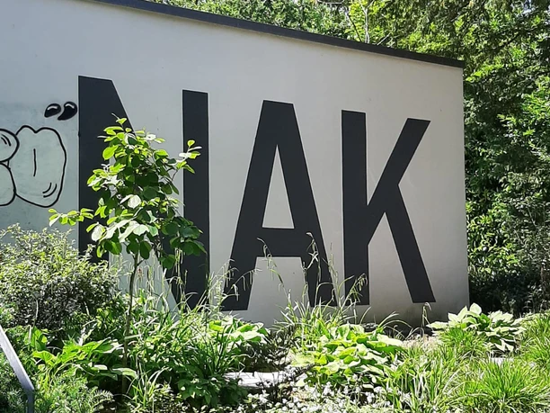Eine weiße Mauer trägt die Aufschrift "NAK".