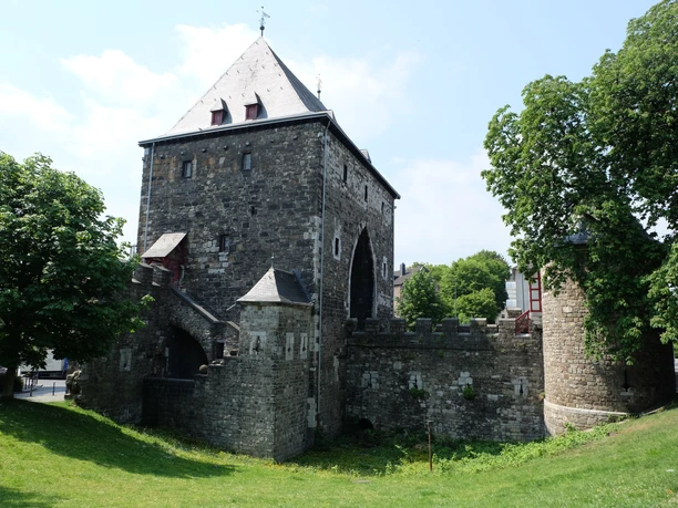Ponttor im Frühling Historisches Stadttor mit zwei Türmen aus Naturstein und einer Wiesen sowie mehreren Bäumen davor.