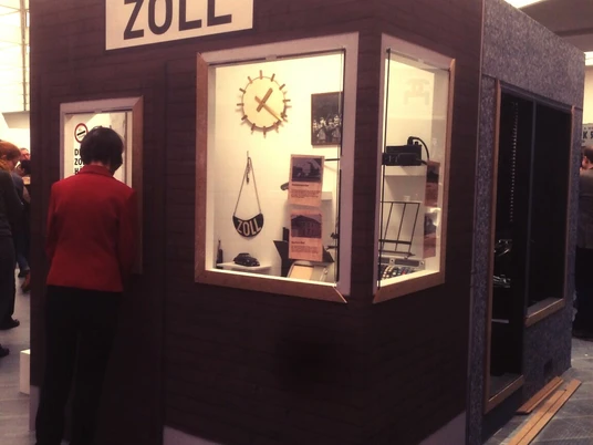 Zollmuseum Ausstellung Eine Frau betrachtet in einem Ausstellungsraum eine alte Zollkabine.