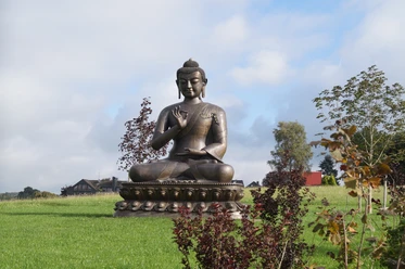 Asiatisches Museum Buddhastatue auf grünem Rasen mit Bäumen und Himmel im Hintergrund in Radevormwald.
