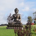 Asiatisches Museum Buddhastatue auf grünem Rasen mit Bäumen und Himmel im Hintergrund in Radevormwald.
