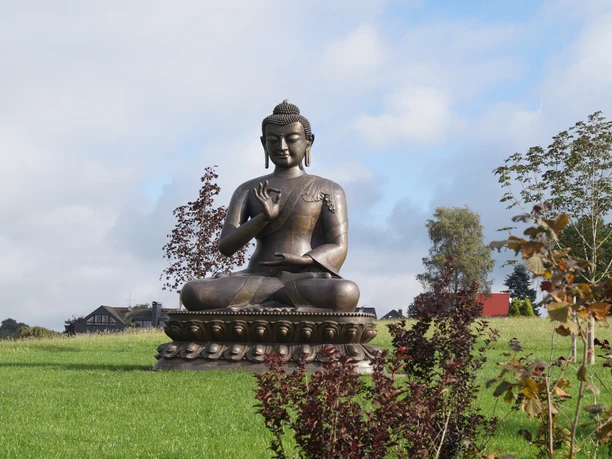 Asiatisches Museum Buddhastatue auf grünem Rasen mit Bäumen und Himmel im Hintergrund in Radevormwald.