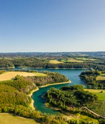 Wahnbachtalsperre Luftaufnahme eines malerischen Sees inmitten sattgrüner Wälder und Felder unter klarem Himmel.