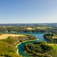 Wahnbachtalsperre Luftaufnahme eines malerischen Sees inmitten sattgrüner Wälder und Felder unter klarem Himmel.
