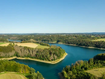 Wahnbachtalsperre Luftaufnahme eines kurvenreichen Flusses in einer grünen Landschaft unter klarem, blauem Himmel.