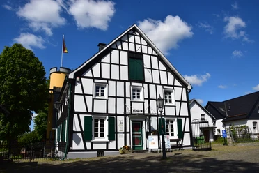 Heimatmuseum Bergneustadt Fachwerkhaus mit Museumsschild, deutscher Flagge, blauen Himmel und historischen Details im Vordergrund.