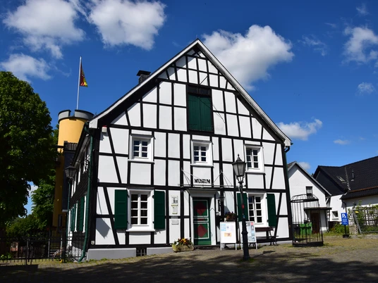 Heimatmuseum Bergneustadt Fachwerkhaus mit Museumsschild, deutscher Flagge, blauen Himmel und historischen Details im Vordergrund.