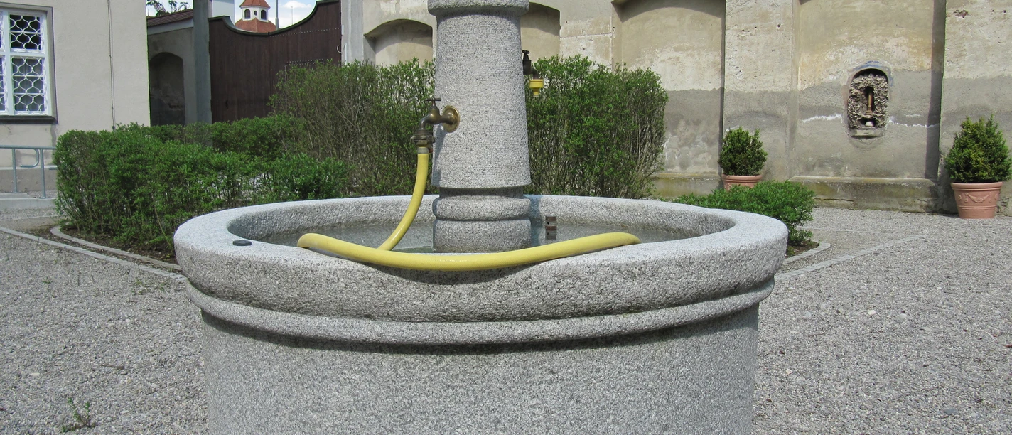 Brunnen mit Gießschlauch im Museumsgarten