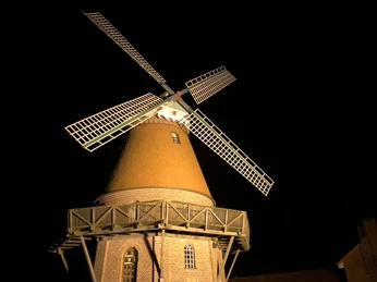 Hochzeitsmühle Landesbergen Eine historische Windmühle mit beleuchtetem Flügelkreuz vor einem dunklen Nachthimmel.A historic windmill with an illuminated winged cross against a dark night sky.En historisk vindmølle med et oplyst vingekors mod en mørk nattehimmel.Een historische windmolen met een verlicht gevleugeld kruis tegen een donkere nachtelijke hemel.