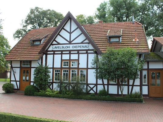 Historischer Fachwerkbahnhof Lavelsloh mit roten Dachziegeln und zwei symmetrischen Eingangstüren.Historic half-timbered Lavelsloh station with red roof tiles and two symmetrical entrance doors.Historisk Lavelsloh-banegård i bindingsværk med røde tagsten og to symmetriske indgangsdøre.Historisch vakwerkstation in Lavelsloh met rode dakpannen en twee symmetrische toegangsdeuren.