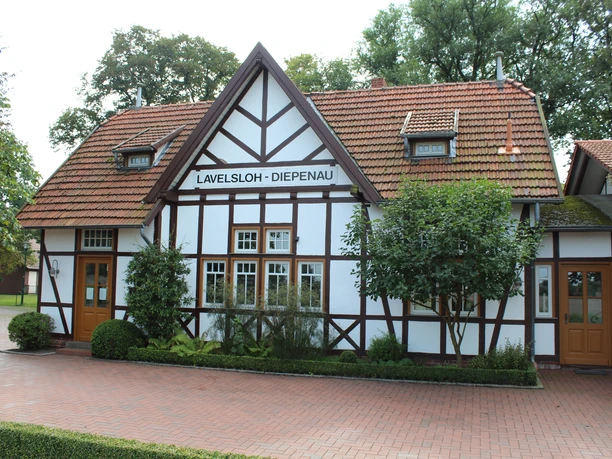 Historic half-timbered Lavelsloh station with red roof tiles and two symmetrical entrance doors.