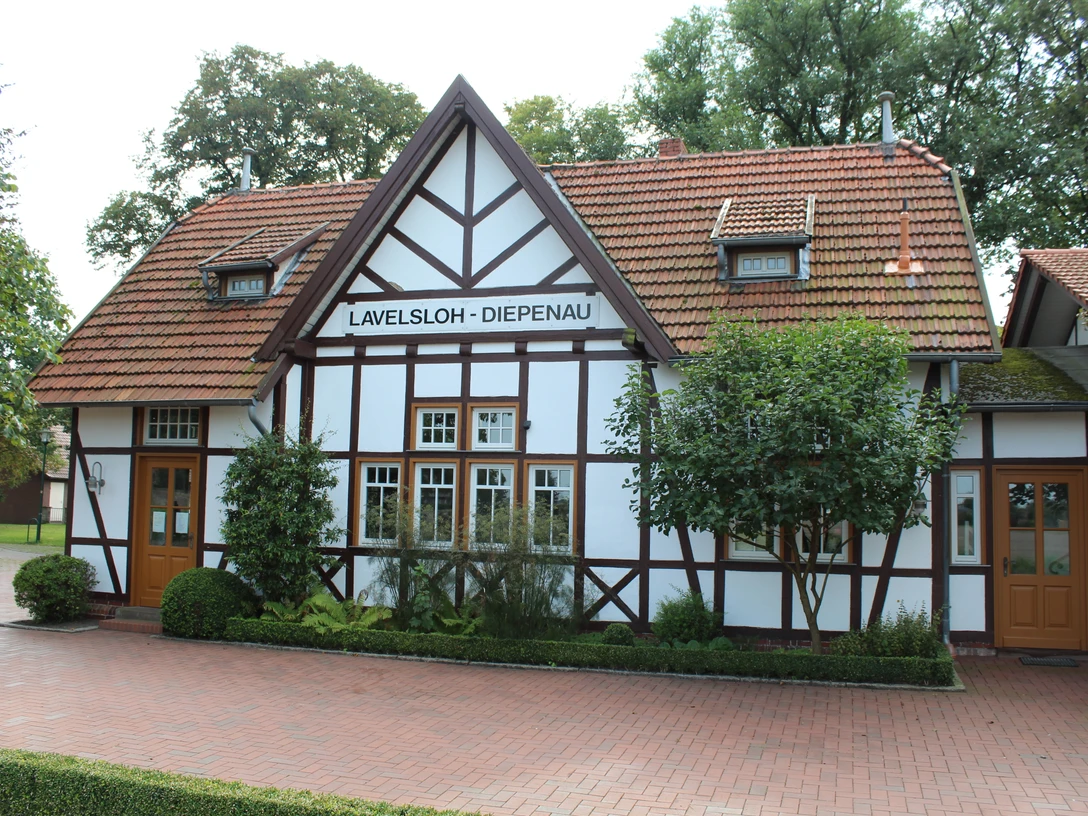 Hochzeitsbahnhof Lavelsloh Historischer Fachwerkbahnhof Lavelsloh mit roten Dachziegeln und zwei symmetrischen Eingangstüren.Historic half-timbered Lavelsloh station with red roof tiles and two symmetrical entrance doors.Historisk Lavelsloh-banegård i bindingsværk med røde tagsten og to symmetriske indgangsdøre.Historisch vakwerkstation in Lavelsloh met rode dakpannen en twee symmetrische toegangsdeuren.