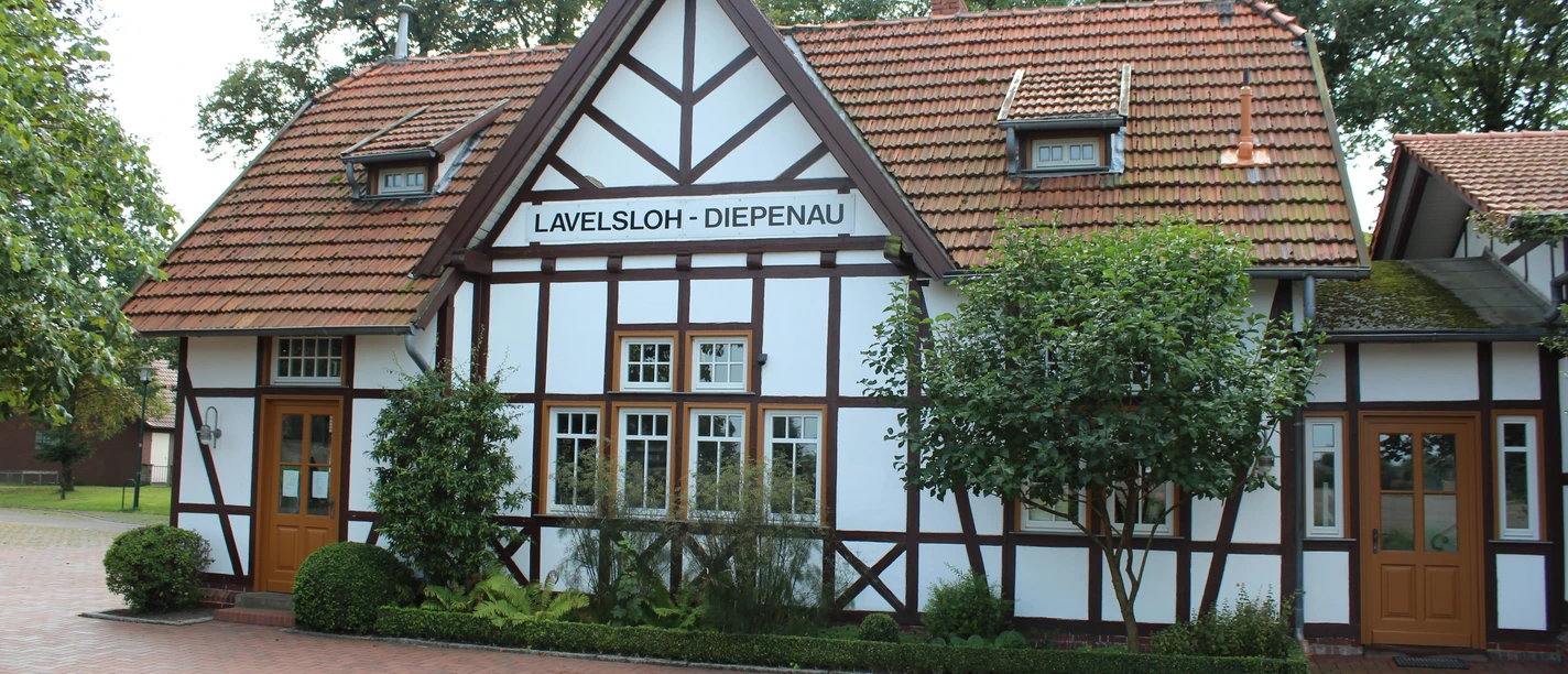Hochzeitsbahnhof Lavelsloh Historischer Fachwerkbahnhof Lavelsloh mit roten Dachziegeln und zwei symmetrischen Eingangstüren.
