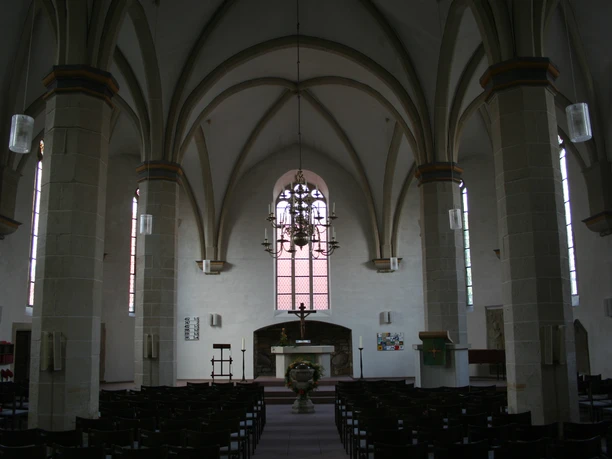 Gotische kerk in Petershagen met hoge gewelven, gekleurde ramen en een sierlijke kroonluchter.