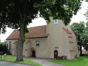 Kirche Ovenstädt Backstein-Kirche in Ovenstädt mit Uhrturm, umgeben von alten Bäumen und mit einem kleinen Vorplatz.