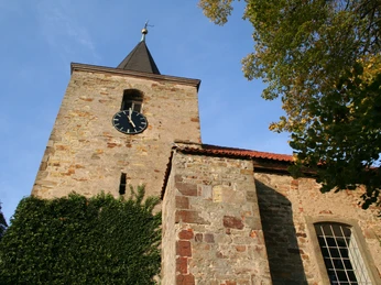 Historische Kirche Nendorf mit Uhrturm aus Backstein, umgeben von Herbstbäumen und klarem Himmel.Historic Nendorf church with brick clock tower, surrounded by autumn trees and a clear sky.Historisk Nendorf-kirke med muret klokketårn, omgivet af efterårstræer og en klar himmel.Historische kerk in Nendorf met bakstenen klokkentoren, omringd door herfstbomen en een heldere hemel.