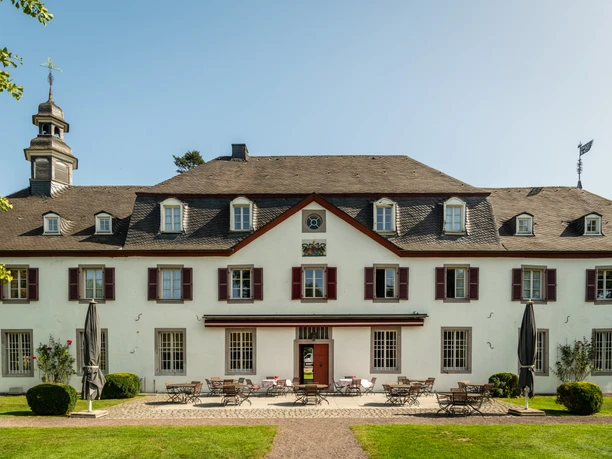 Schloss Auel Historische Villa mit symmetrischer Fassade, roten Fensterläden und Schieferturmdach.